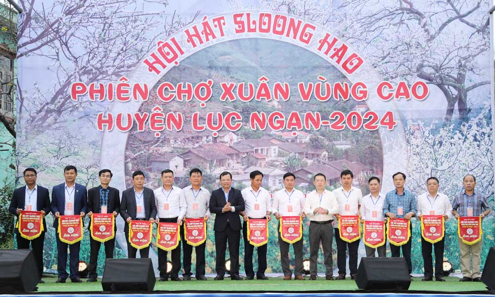 Các đồng chí Phan Thế Tuấn và Vương Tuấn Nghĩa, Bí thư Huyện ủy Lục Ngạn trao cờ lưu niệm cho đại diện các đơn vị tham dự hội hát.