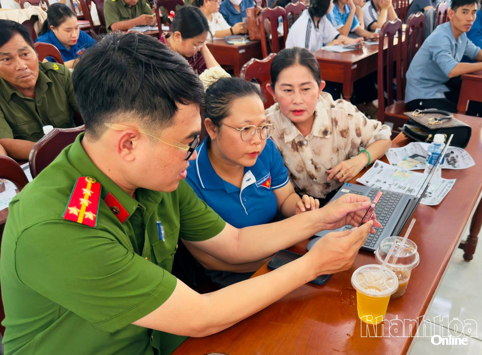 Cán bộ Công an xã Phước Hậu hướng dẫn các đại biểu sử dụng và khai thác các tiện ích trên ứng dụng VNeID.
