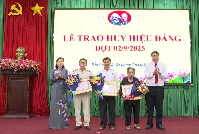 Phó Bí thư Đảng ủy, Chủ tịch UBND phường Bến Cát Trần Thị Thảo cùng lãnh đạo phường trao Huy hiệu Đảng cho các đảng viên