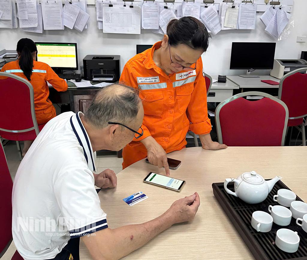 Cán bộ ngành điện hướng dẫn khách hàng sử dụng App CSKH và thanh toán tiền điện qua ngân hàng.