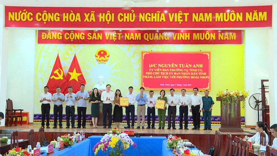 Phó Chủ tịch UBND tỉnh Nguyễn Tuấn Anh (thứ 6 từ trái sang) tặng quà cho lãnh đạo phường Hoài Nhơn. Ảnh: Phi Long