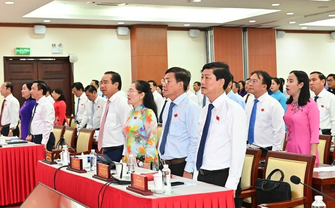 Các đại biểu dự kỳ họp thực hiện nghi thức chào cờ. (Ảnh: SGGP)