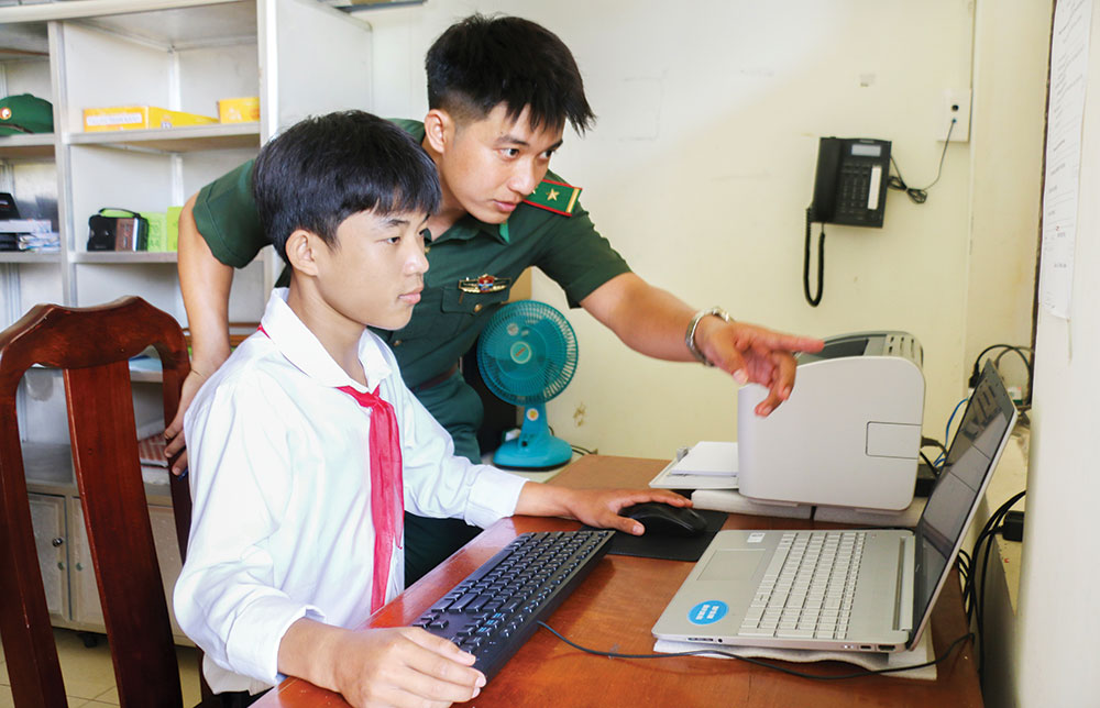 Trung úy Nguyễn Quốc Nam- Đồn Biên phòng Long Hòa hướng dẫn em Nguyễn Văn Tài kỹ năng giải toán trên máy tính. ẢNH: SƠN TUYỀN