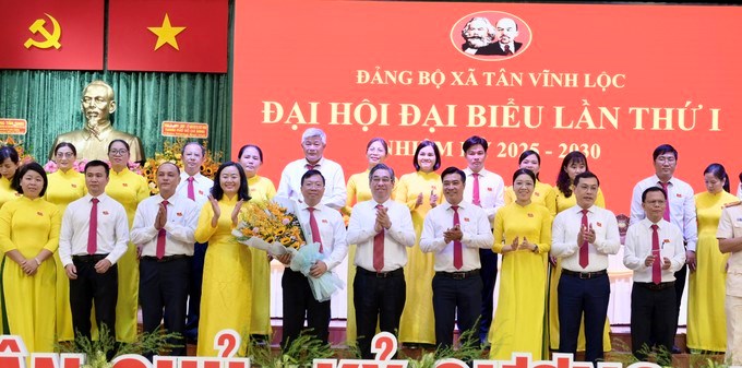 Đồng chí Nguyễn Phước Lộc tặng hoa chúc mừng Ban Chấp hành Đảng bộ xã. Ảnh: SGGP