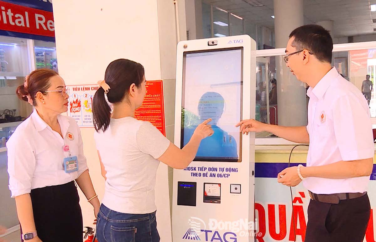 Nhân viên y tế hướng dẫn bệnh nhân đăng ký khám bệnh bằng kiosk Y tế thông minh. Ảnh: Nhất Phương