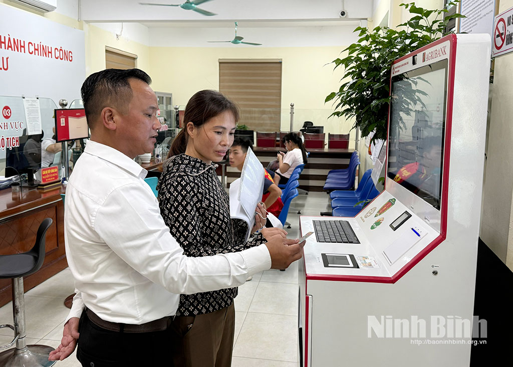 Cán bộ phường Đông Hoa Lư hướng dẫn người dân sử dụng Ki-ốt hành chính công thông minh phục vụ giải quyết thủ tục hành chính trực tuyến. Ảnh: Nguyễn Hương