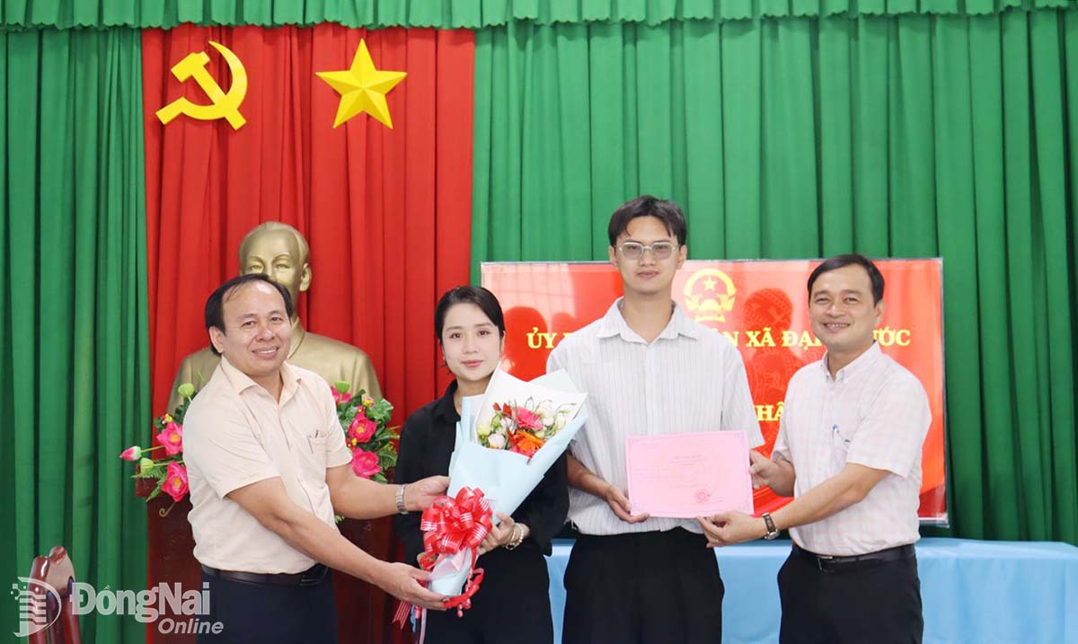 Phó Giám đốc Sở Nội vụ tỉnh Đồng Nai Hà Thanh Tùng (bìa trái) và Phó Chủ tịch UBND xã Đại Phước Phan Chí Thảo tặng hoa, trao giấy chứng nhận kết hôn và thư chúc mừng anh Kiệt, chị Trang. Ảnh: Nam Anh