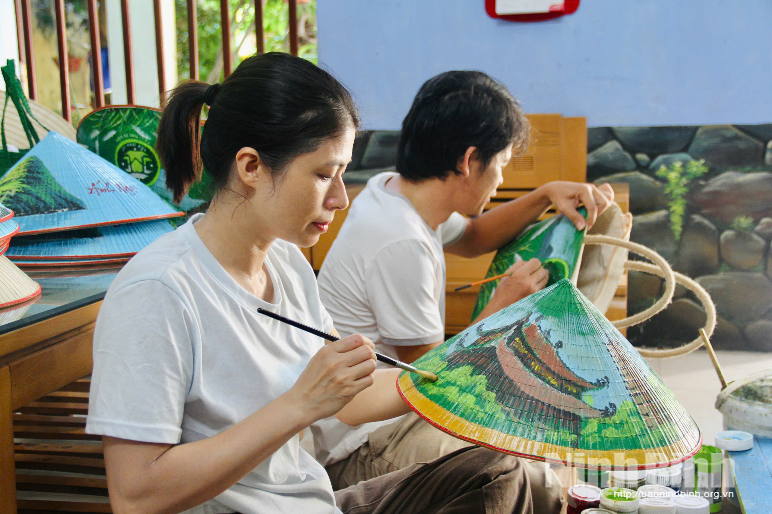Chị Lã Phương Hằng tỉ mỉ vẽ từng đường nét trên nón lá.