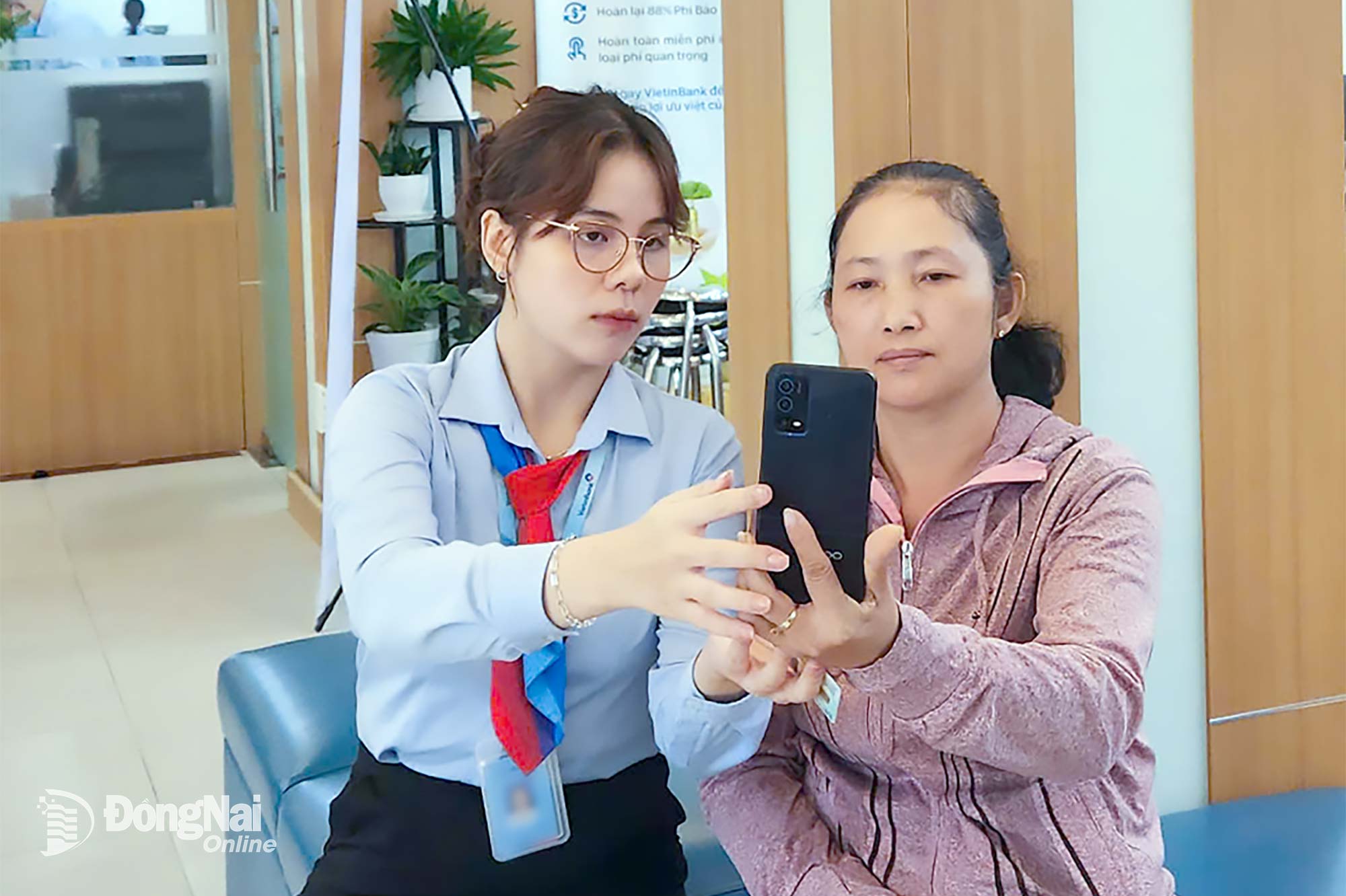 Nhân viên một chi nhánh ngân hàng ở phường Trấn Biên hỗ trợ khách hàng thực hiện xác thực sinh trắc học cho tài khoản ngân hàng. Ảnh: Hải Quân