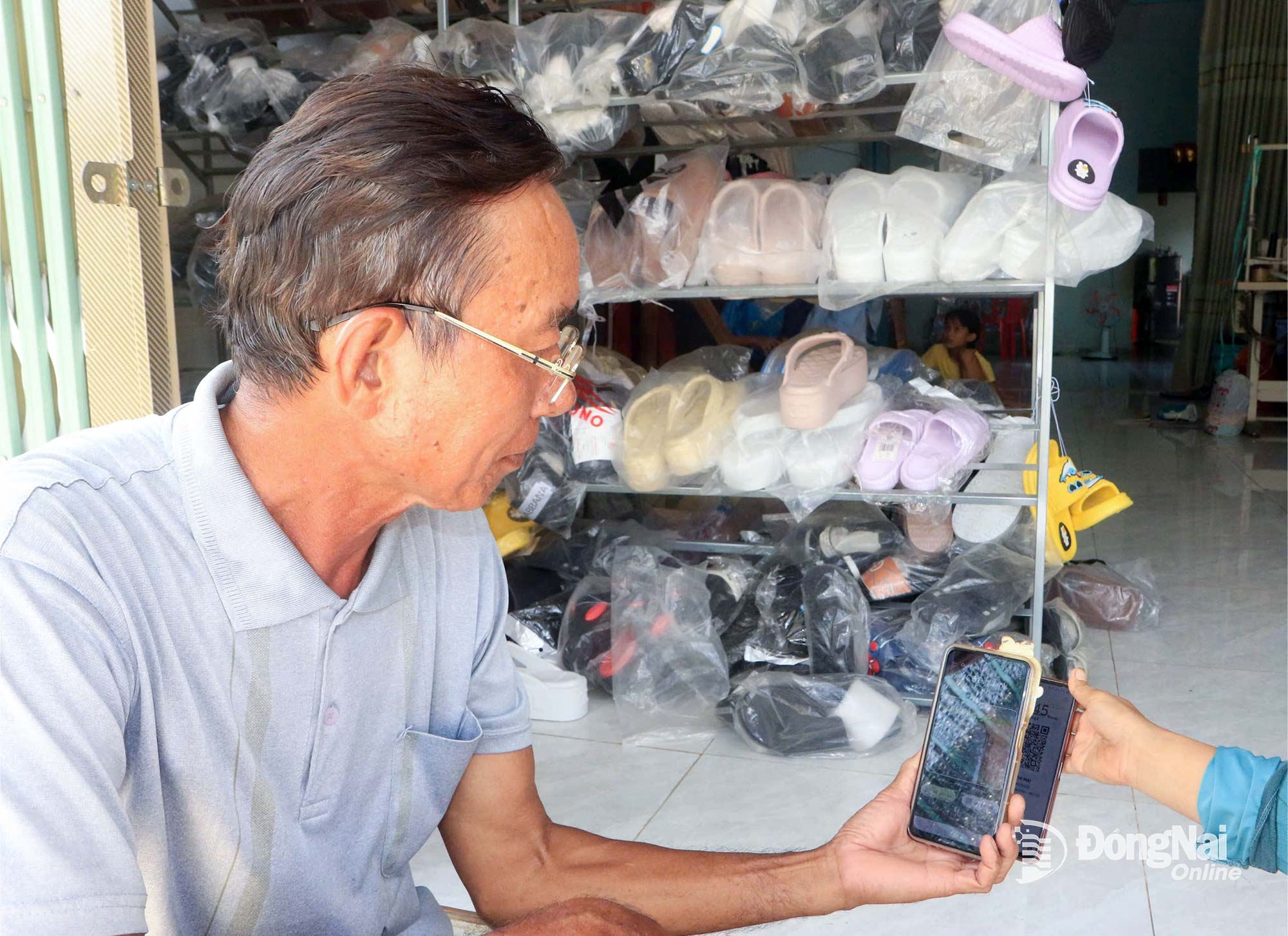 Ông Hoàng Văn Thái (dân tộc Dao), người có uy tín trong đồng bào dân tộc thiểu số ấp 6, xã Thanh Sơn, trả tiền mua hàng bằng hình thức chuyển khoản.