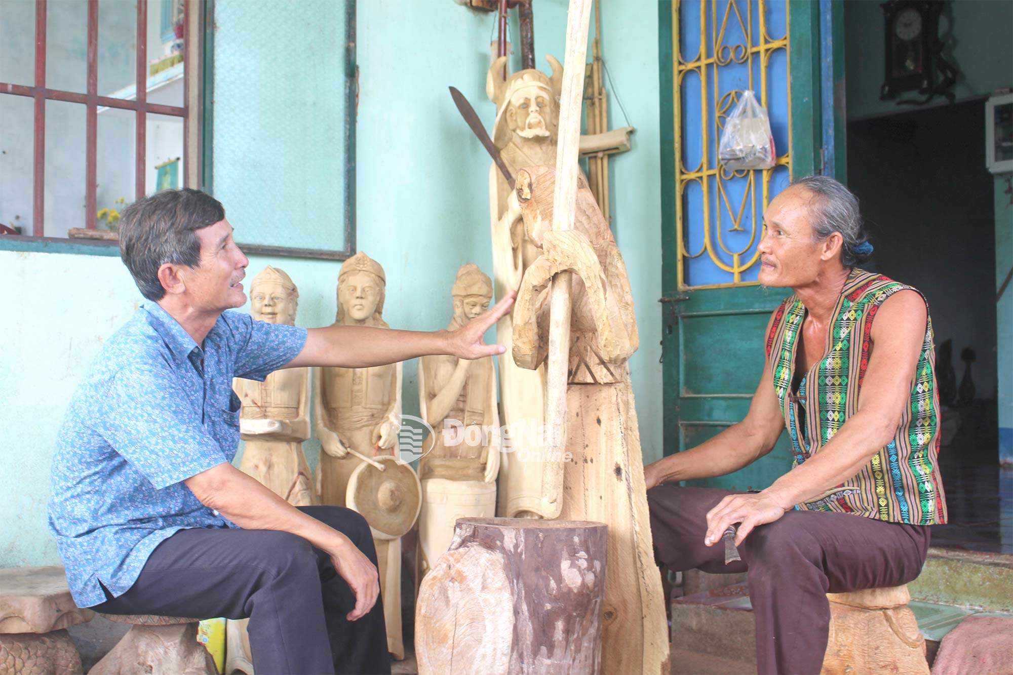 Ông Nguyễn Đình Du (bìa phải, ngụ xã Thống Nhất) kể chuyện lịch sử, văn hóa người Mường qua tạc tượng gỗ.