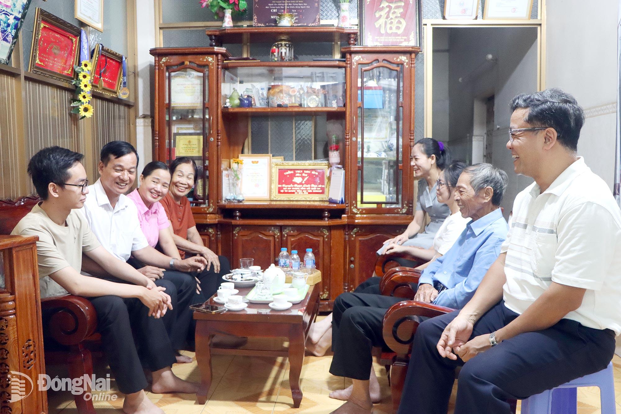 Phó Bí thư chi bộ, Trưởng khu phố 1, phường Long Bình Đàm Văn Nhượng (thứ hai bên trái) và Trưởng ban Công tác Mặt trận khu phố 1 Chu Thị Trinh (thứ ba bên trái) trò chuyện cùng đại gia đình 3 thế hệ cựu chiến binh Nguyễn Văn Nhuận. Ảnh: PV