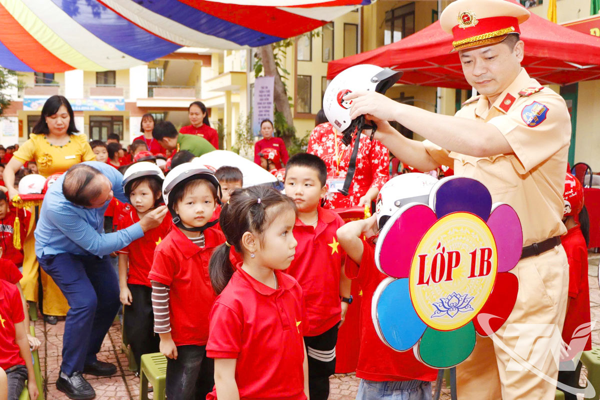 Các thành viên Ban Tổ chức hướng dẫn đội mũ đúng quy cách cho các em học sinh lớp 1 tại chương trình.
