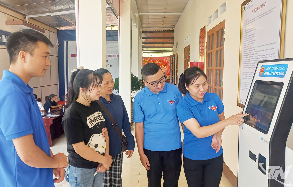 Đoàn viên thanh niên xã Yên Trạch hướng dẫn người dân sử dụng ứng dụng công nghệ số tại Trung tâm Phục vụ hành chính công của xã.