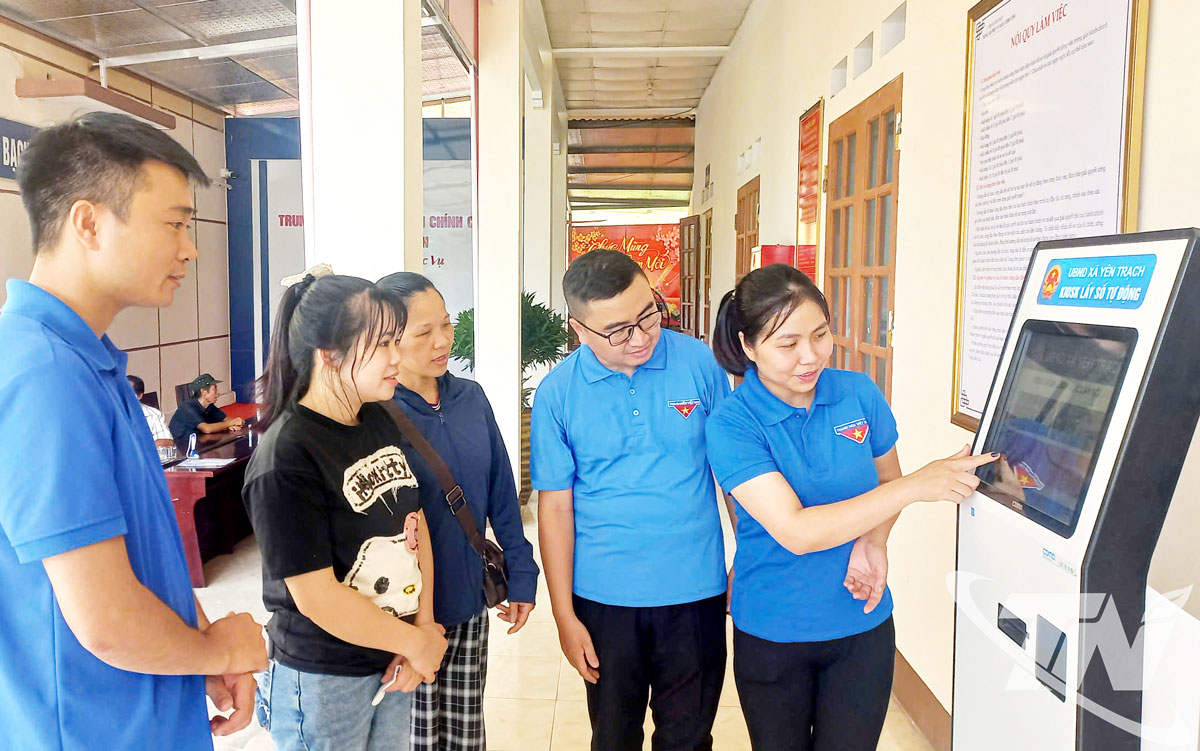 Đoàn viên thanh niên xã Yên Trạch hướng dẫn người dân lấy số thứ tự tại Trung tâm Phục vụ hành chính công của xã.