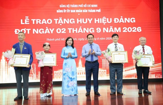 Đồng chí Nguyễn Văn Được, Bí thư Đảng ủy UBND TPHCM, Chủ tịch UBND TPHCM và đồng chí Nguyễn Thanh Xuân, Phó Bí thư Đảng ủy UBND TPHCM trao Huy hiệu Đảng. Ảnh: LÊ THOA