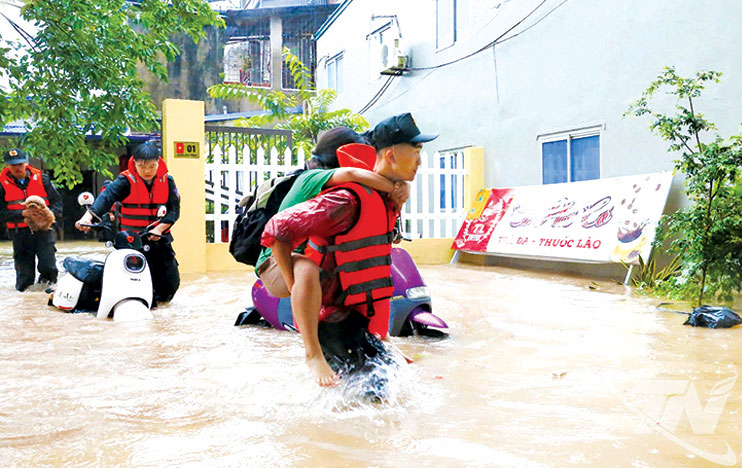 Lực lượng chức năng hỗ trợ đưa người dân ra khỏi khu vực ngập lụt đến nơi an toàn.