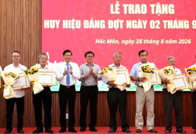 Đồng chí Trần Văn Tuấn cùng lãnh đạo xã Hóc Môn trao Huy hiệu Đảng đến đảng viên. Ảnh: NGÔ BÌNH