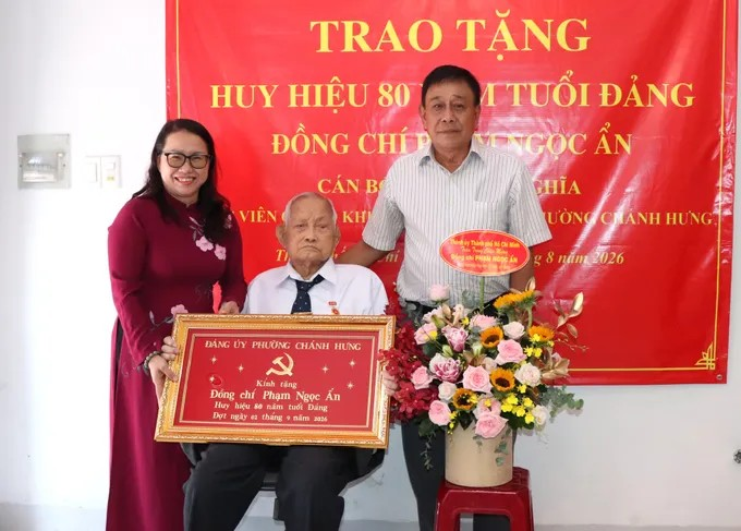 Đại diện phường Chánh Hưng và chi bộ khu phố 46 chúc mừng đồng chí Phạm Ngọc Ẩn nhận Huy hiệu 80 năm tuổi Đảng. Ảnh: THÁI PHƯƠNG