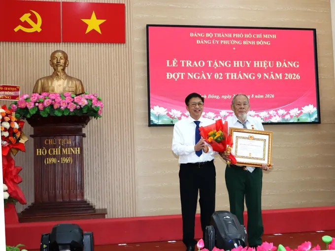 Bí thư Đảng ủy phường Bình Đông Võ Thành Khả trao Huy hiệu Đảng đến đảng viên. Ảnh THÁI PHƯƠNG.