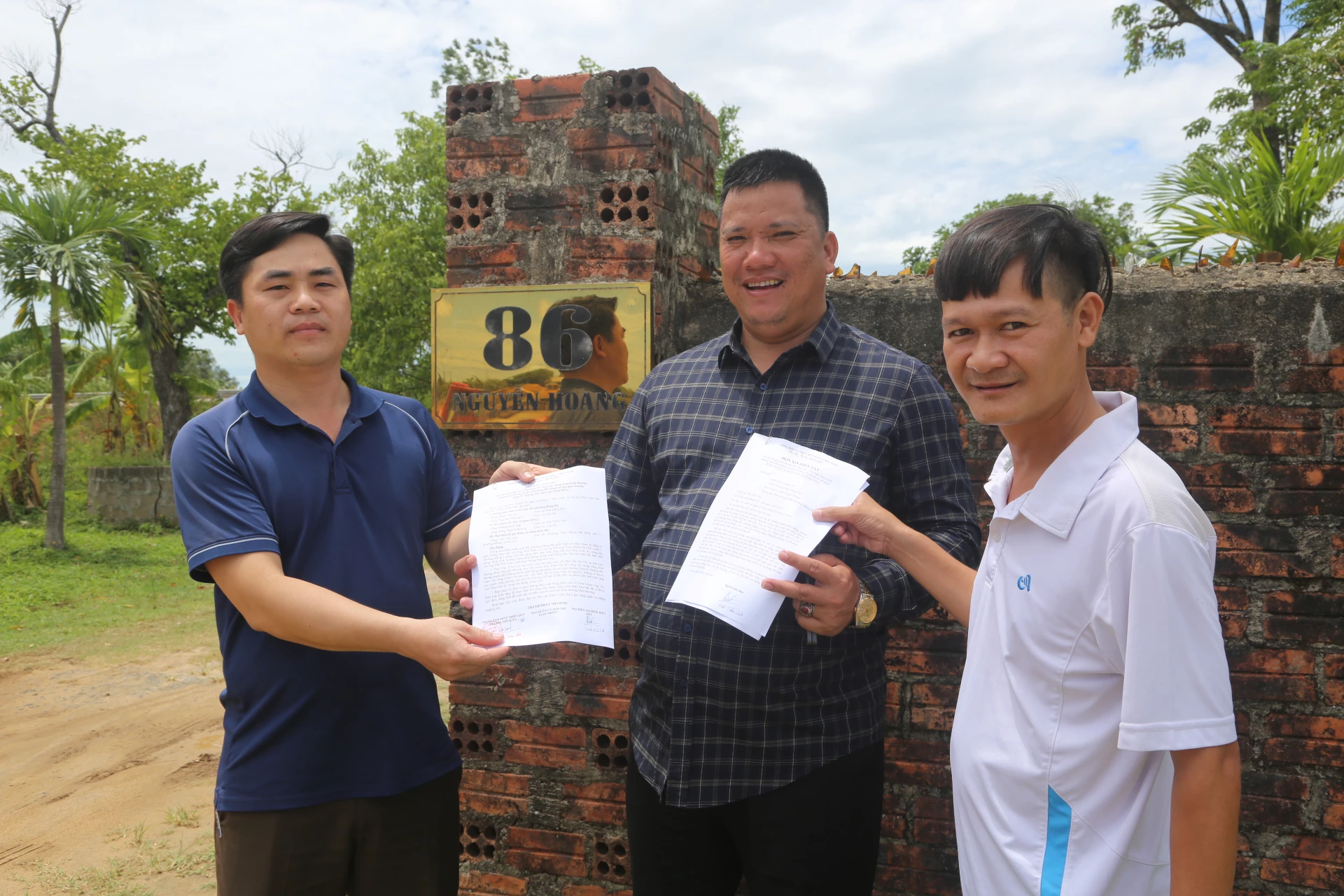 Ông Văn Tiến Lực trao đơn xin tự nguyện hiến đất và biên bản hiến đất cho 2 cán bộ Trung tâm Phát triển quỹ đất phường Đông Hà và Ban Quản lý Bảo trì giao thông, Sở Xây dựng - Ảnh: LÊ MINH