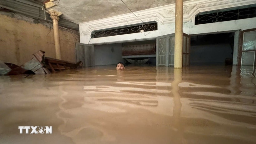 Ông Lê Bình (thôn Cửa Hà, xã Cẩm Thủy, Thanh Hóa) phải bơi trong ngôi nhà bị ngập sâu gần 2m để cố vớt vát các tài sản còn lại. (Ảnh: Việt Hoàng/TTXVN)