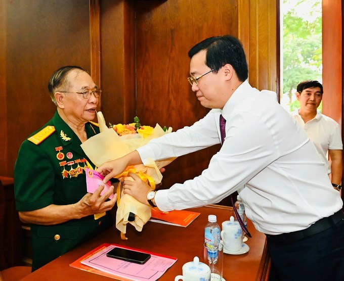 Phó Bí thư Thường trực Thành ủy TPHCM Lê Quốc Phong tặng hoa Anh hùng Đại tá LLVT Đặng Trung Thành . (Ảnh: SGGP)