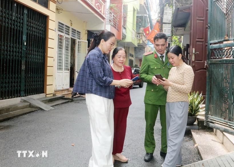 Tổ công nghệ số cộng đồng cùng cán bộ công an phường Phủ Lý, tỉnh Ninh Bình đến từng khu dân cư hướng dẫn người dân tham gia góp ý dự thảo các văn kiện Đại hội XIV của Đảng thông qua ứng dụng VNeID. (Ảnh: Nguyễn Chinh/TTXVN)