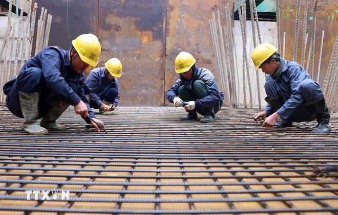 Các kỹ sư, công nhân đang ngày đêm "vượt nắng, thắng mưa" để đảm bảo tiến độ thi công Dự án. (Ảnh: Quốc Khánh/TTXVN) ttxvn-cau-duong-bo-bien-gioi-qua-song-hong-6.jpg