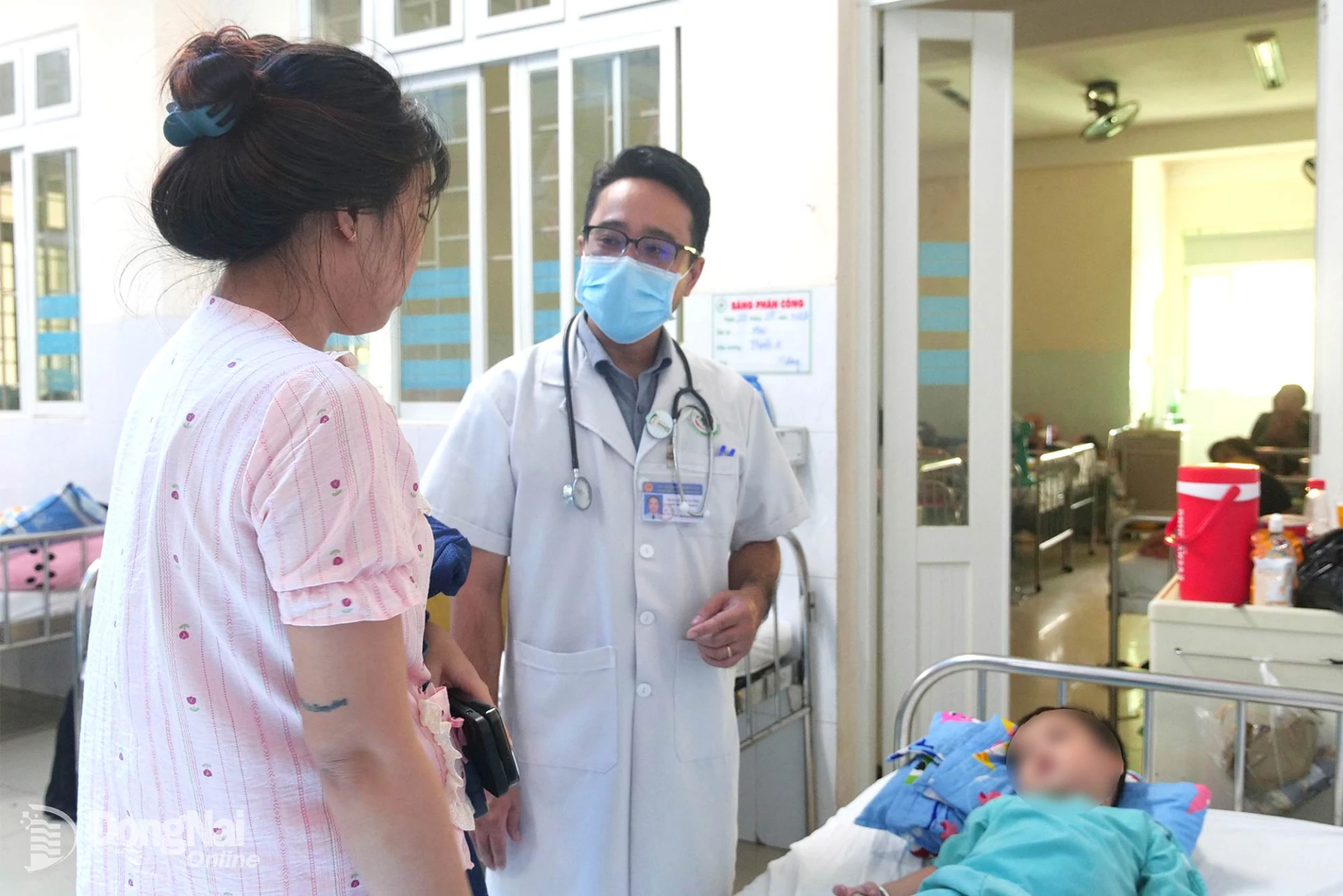 Thạc sĩ, bác sĩ Trần Lê Duy Cường, phụ trách Khoa Hô hấp, Bệnh viện Nhi đồng Đồng Nai thăm khám cho bệnh nhi và hướng dẫn phụ huynh cách chăm sóc trẻ. Ảnh: Hạnh Dung